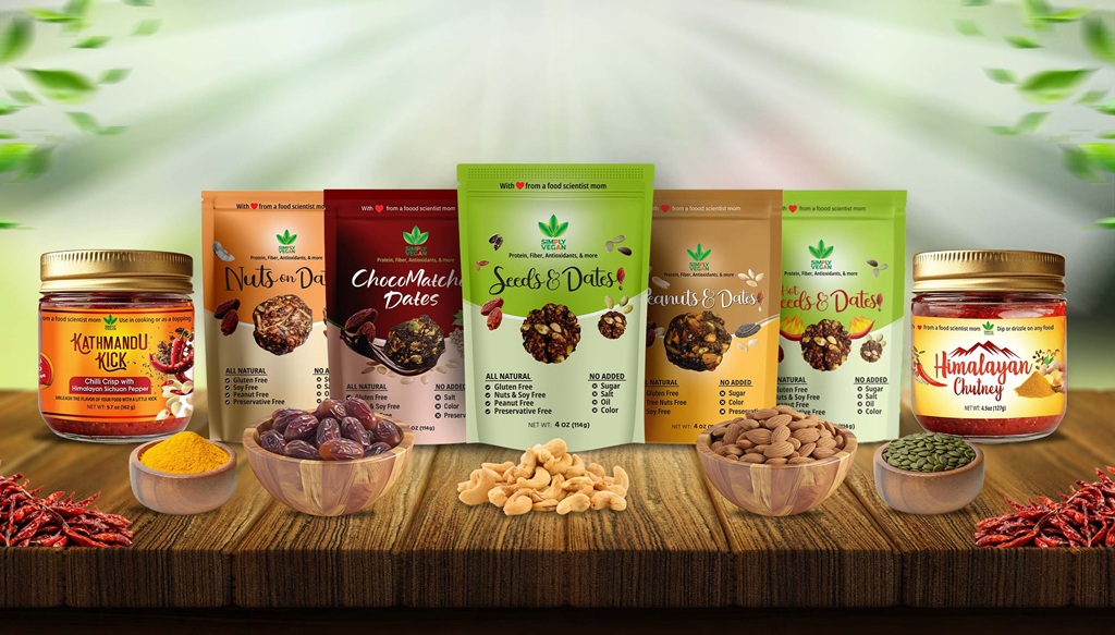 A wooden table showcasing spicy pickles and healthy snacks from Simply Vegan, using nuts, dates, seeds, and a variety of plant-based foods.